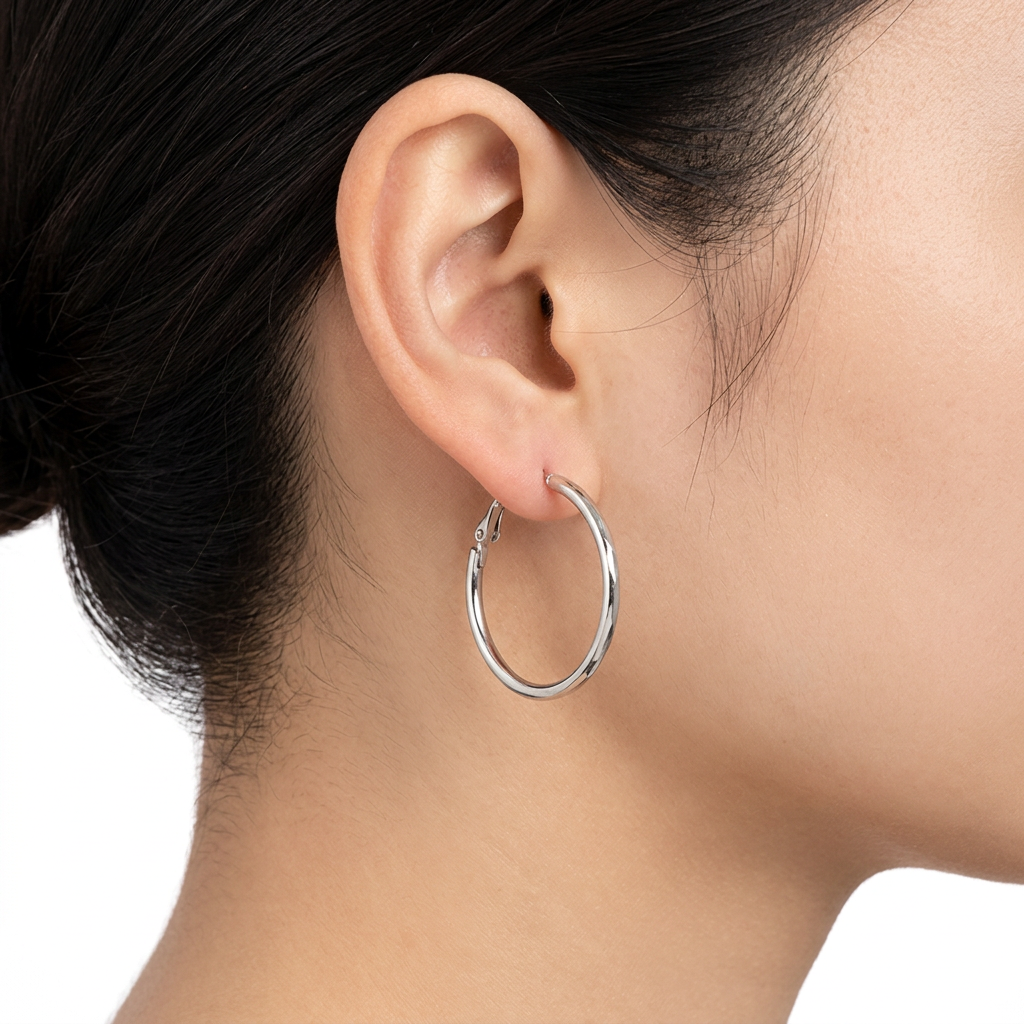 Srebrny cienki kolczyk kółko na uchu modelki na białym tle